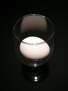 Ovo branco em copo com pé em fundo negro