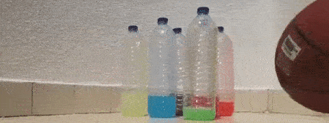 (Vídeo curto) 6 garrafas de plástico transparente com líquidos coloridos derrubadas por uma bola