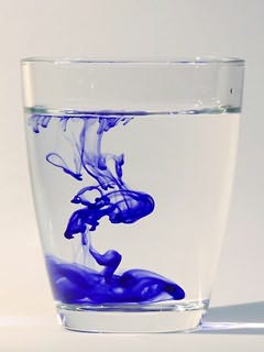 Copo com tinta azul espalhando-se na água