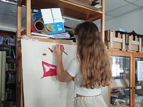 Menina vista de costas pintando painel