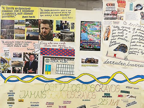 Cartazes em cartolina com fotos e citações sobre educação colados em papel cenário.