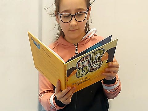 Menina de óculos e pé lendo livro