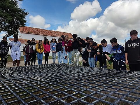 Grupo de jovens à volta de grade colocada por cima de buraco grande