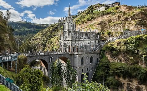 Basílica e ponte sobre um desfiladeiro em paisagem montanhosa e verdejante