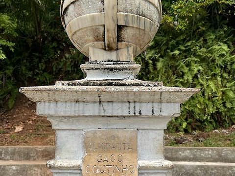 Pormenor de pedestal de pedra com esfera armilar no topo e, a meio, placa com inscrição «Ao Almirante Gago Coutinho»