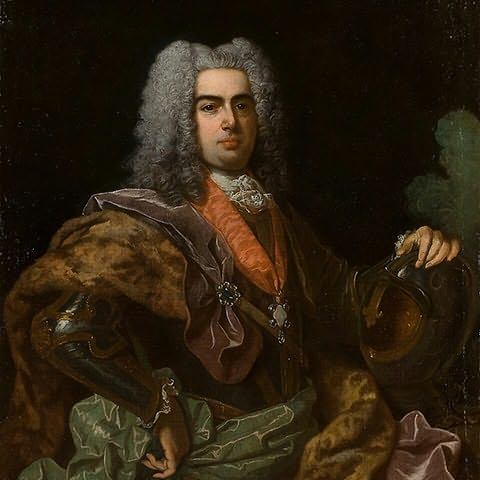 Homem com cabelo grisalho aos cachos segurando um capacete de metal e uma ins&iacute;gnia ao peito