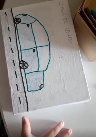 Carro contornado a marcador azul em estrada delineada a marcador preto em tampa de caixa