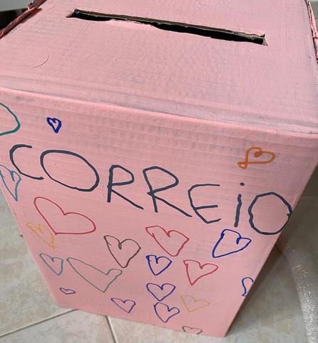 Caixa de cartão pintada de cor-de-rosa transformada em caixa de correio, decorada com corações coloridos a marcador