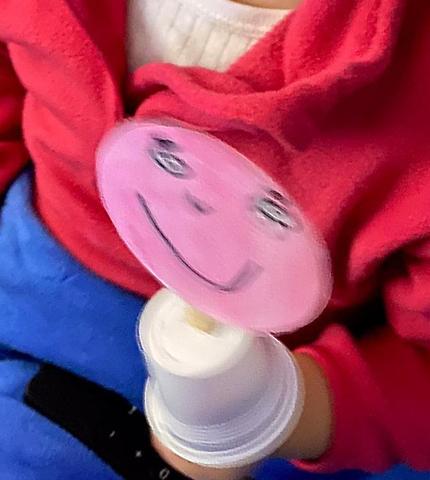 Menina com fantoche de emoções construído com copo e espátula de café e cara em cartão colorida a cor-de-rosa
